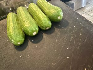 Close-up photo of mini cucumbers showing the blossom end, on a black plastic cutting board